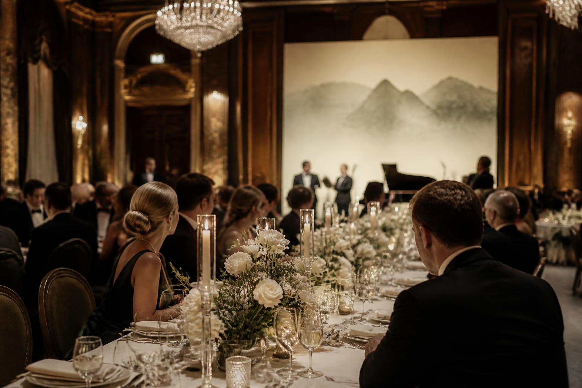 Black tie brand dinner in a grand hall, candlelit tables and white florals